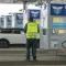 Bulgarian border police officer in high-vis vest inspecting white SUV with open boot at customs checkpoint with migration control booths visible