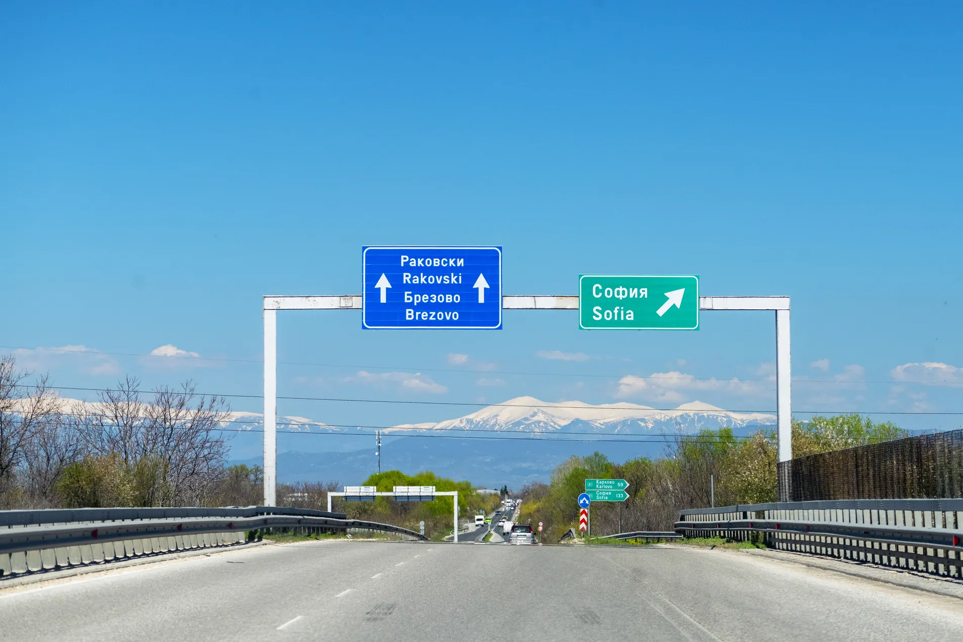 Bulgaria motorway overhead signs directing to Sofia, Rakovski and Brezovo with snow-capped Balkan mountains visible in background