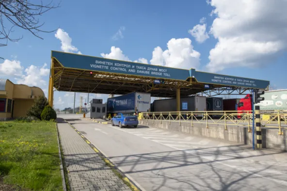 Bulgaria vignette control and Danube Bridge toll checkpoint with cars and trucks passing under overhead gantry sign in Bulgarian and English