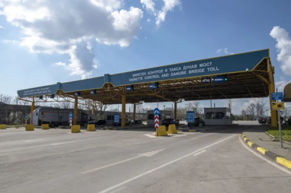 Bulgaria vignette control and Danube Bridge toll plaza with multiple payment lanes, ePay sign and yellow canopy structure with cars and trucks passing through