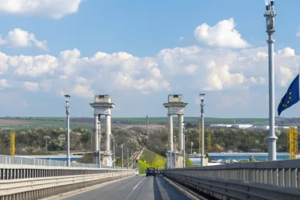 Historic Danube Bridge between Ruse Bulgaria and Giurgiu Romania built 1952-1954 with ornate stone pillars, EU flag and railway track visible below on a sunny day